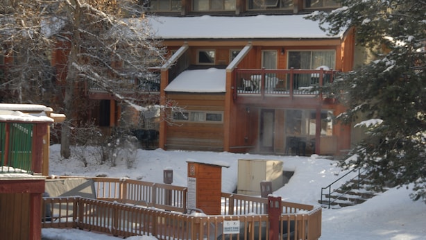 Une cabane en bois dotée d’un balcon, entourée d’arbres couverts de neige.