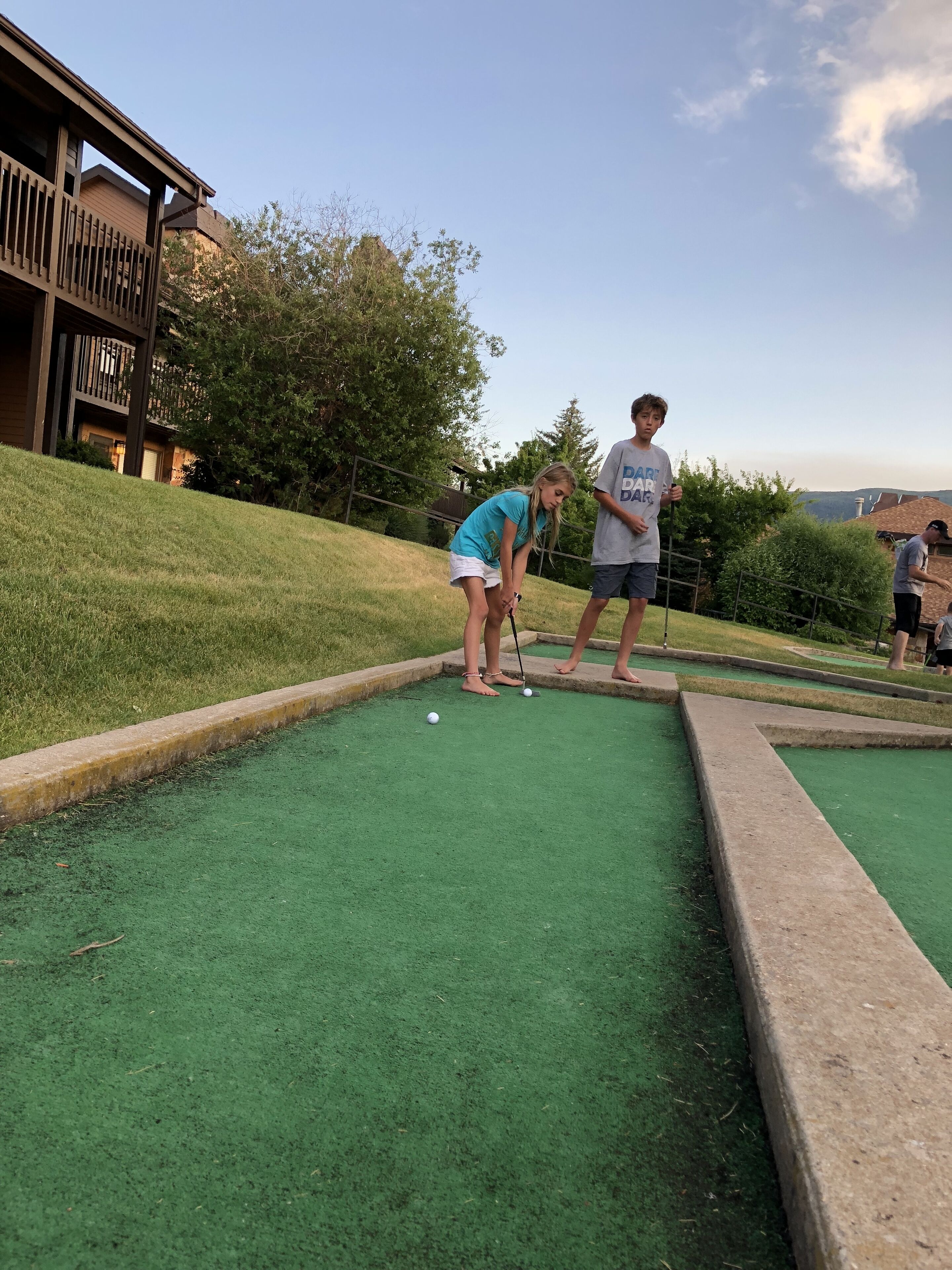 A golf course with a putting green and a wooden fence.