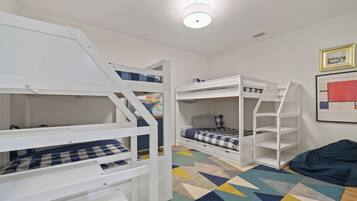 Cozy room with bunk beds, a framed picture, and a shelving unit.
