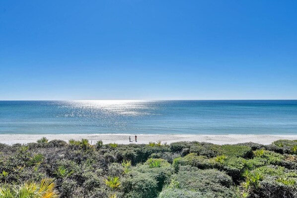 A beach with a clear view of the ocean and a few people in the distance.