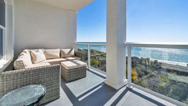 A balcony with a wicker sofa and a small table, overlooking a coastal landscape. - Seabiscuit -Scenic 30A, Phenomenal Gulf Front Condo w/Spectacular Views! (Rosemary Beach)