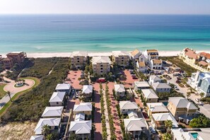 An aerial view of a coastal resort with multiple buildings, a beach, and a clear view of the ocean.