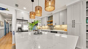A modern kitchen with white cabinetry, a large marble island, and pendant lighting. - Seabiscuit -Scenic 30A, Phenomenal Gulf Front Condo w/Spectacular Views! (Rosemary Beach)