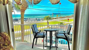 Ein Zimmer mit Meerblick, ein Balkon mit Tisch und Stühlen sowie ein gemustertes Sofa.