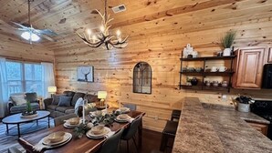 Interior de una cabaña de madera con comedor, cocina y sala de estar.