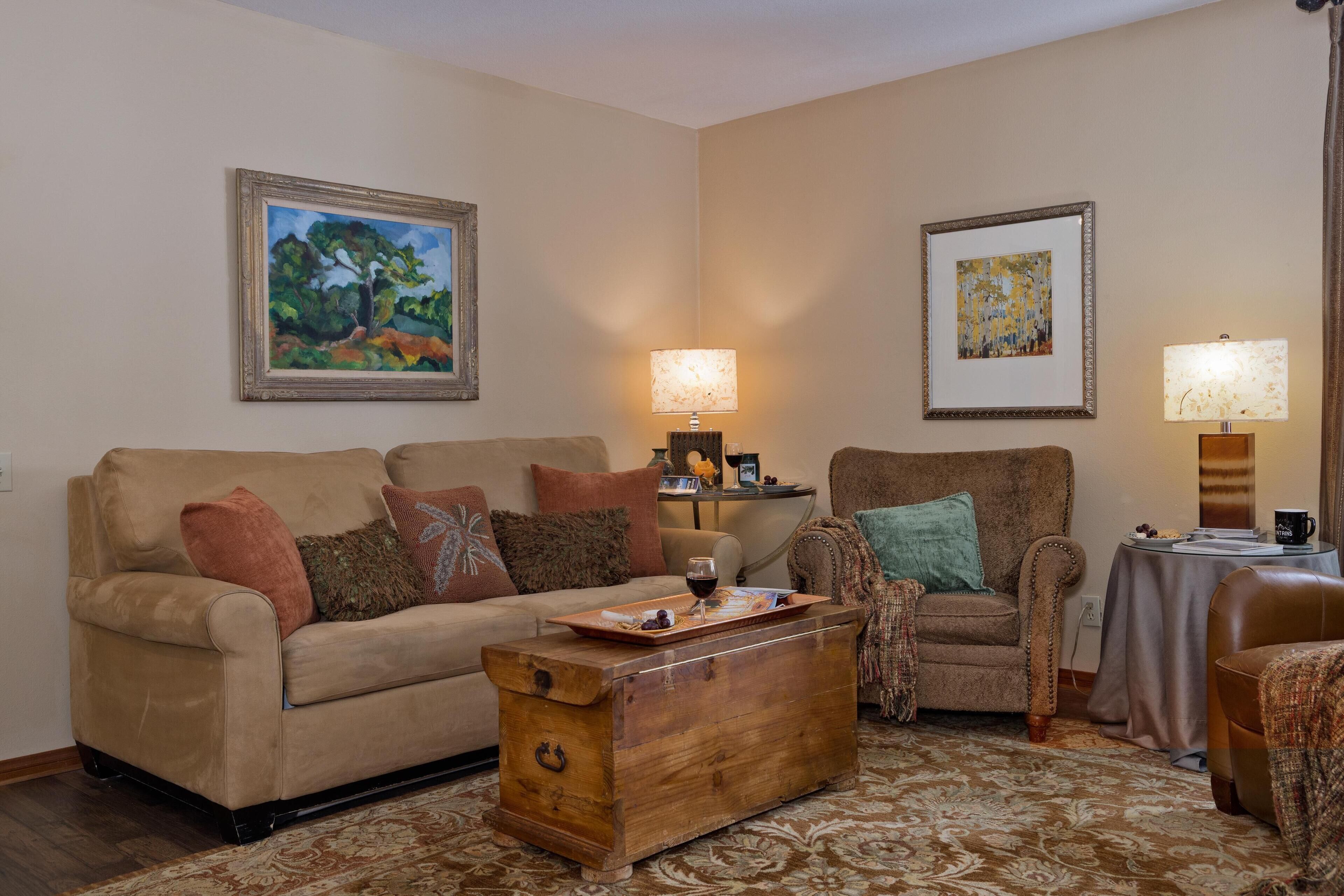 A living room with a sofa, armchair, wooden coffee table, and two lamps.