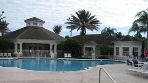 A swimming pool area with a covered deck, palm trees, and a building with a dome-shaped roof. - S-Facing Pool, 3.6 mi from Disney, man-gated resort, wheelchair accessible (Kissimmee)
