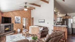 Ein geräumiges Wohnzimmer mit Kamin, Ledersofas, einem Essbereich und einer Küche mit Holzschränken.