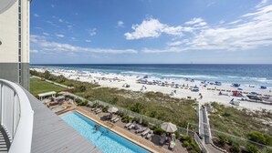 Blick auf einen Pool mit Strand und Meer im Hintergrund.