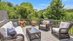 A deck with wicker furniture, including a sofa and chairs, and a glass-top coffee table. - The Big Blue House - 6000sf of Luxury in Leiper's Fork (Franklin)