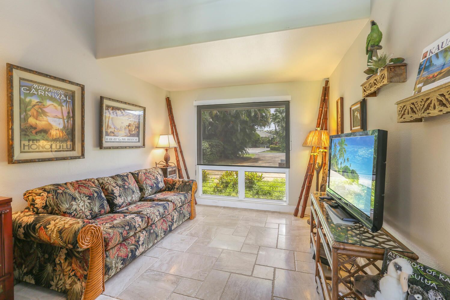 A living room with a sofa, television, and framed pictures on the wall.