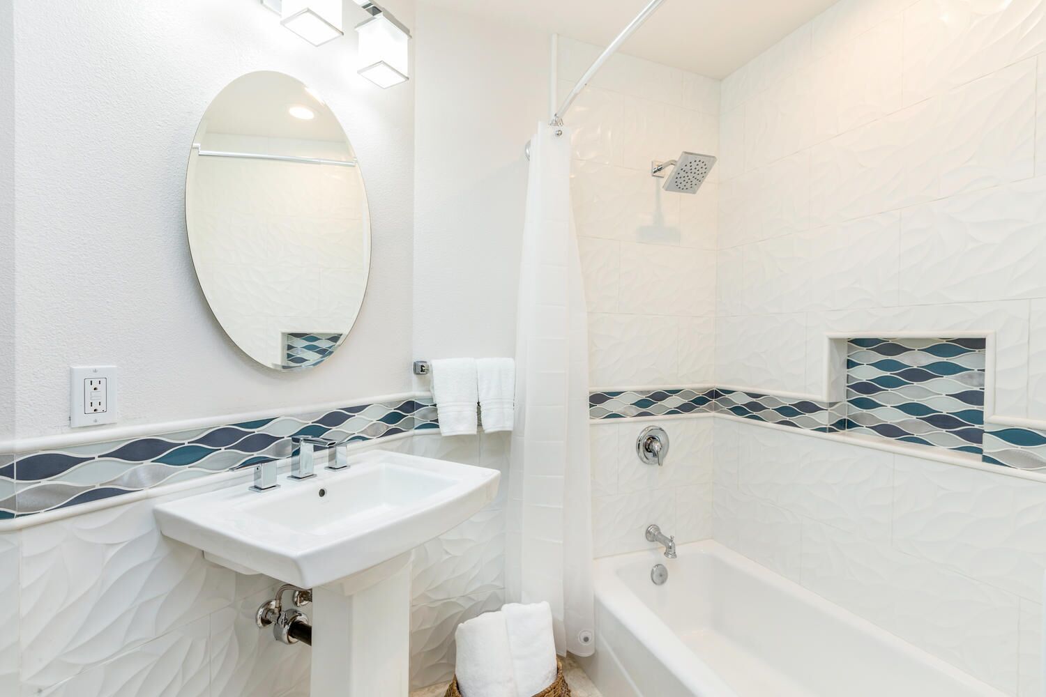Un baño con lavamanos blanco, un espejo, ducha y bañera.