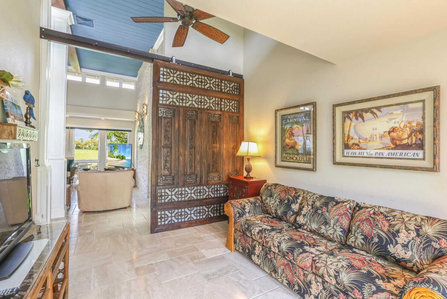 A living room with a sofa, a coffee table, a television, and a decorative screen door.