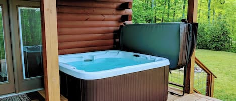 Ein Whirlpool auf einer Holzterrasse mit Blick auf einen Wald.