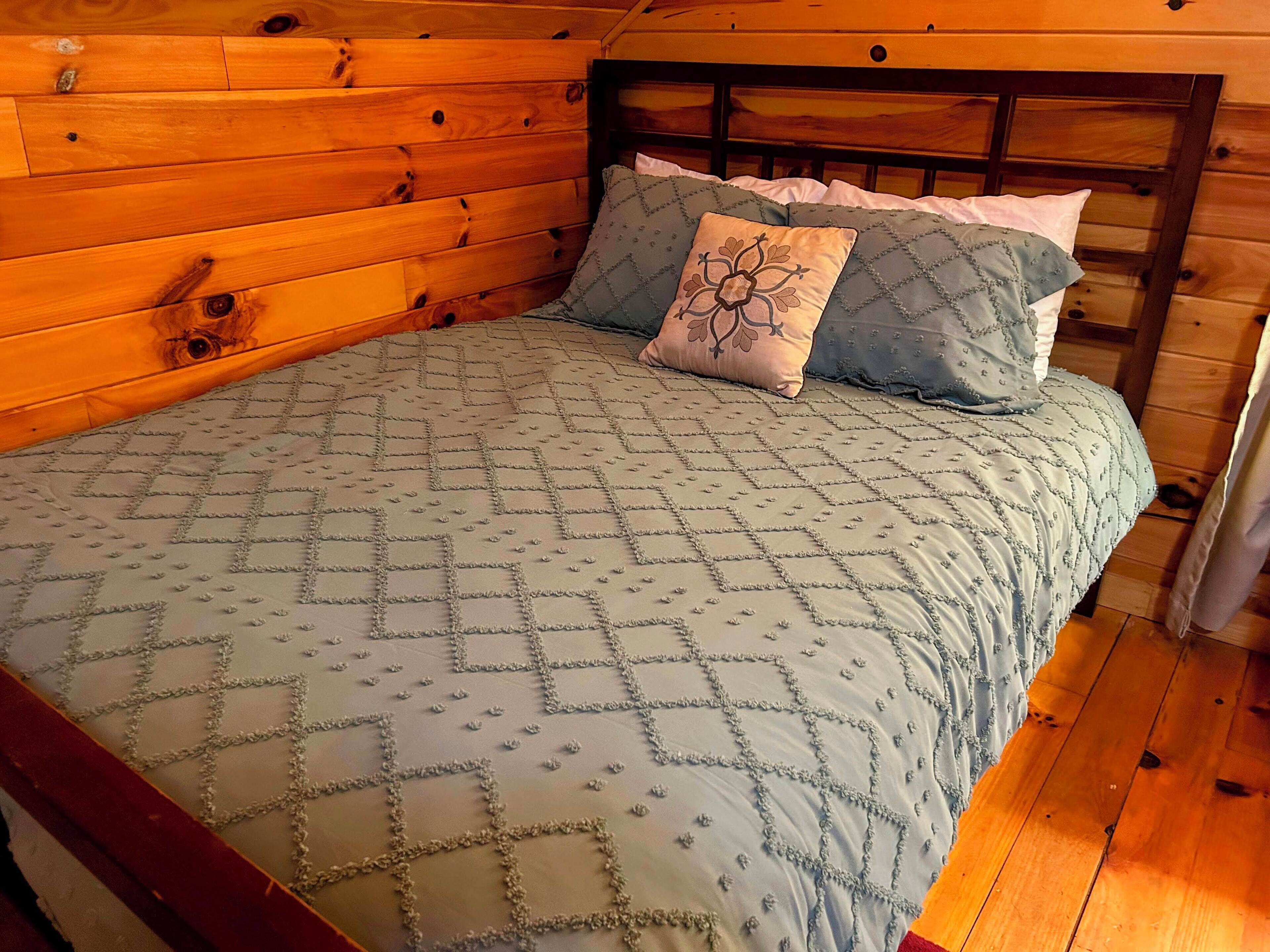 Una camera in una baita di legno, con un letto, una testiera e una finestra.