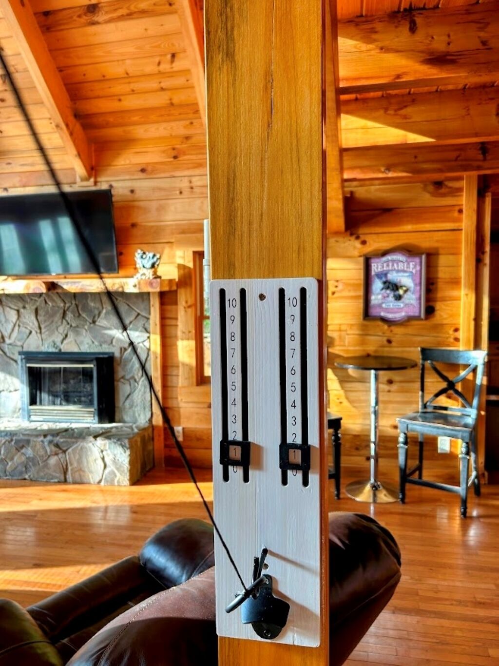 A wooden interior with a stone fireplace, a mounted television, and a wall-mounted device with numbered slots.