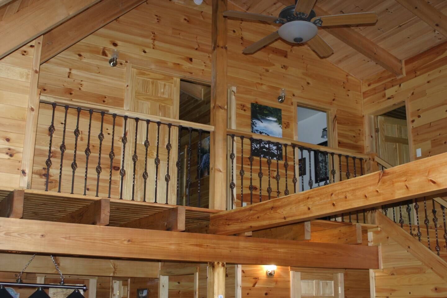L’intérieur d’un chalet en bois, avec un escalier en bois, un ventilateur de plafond et une fenêtre offrant une vue.