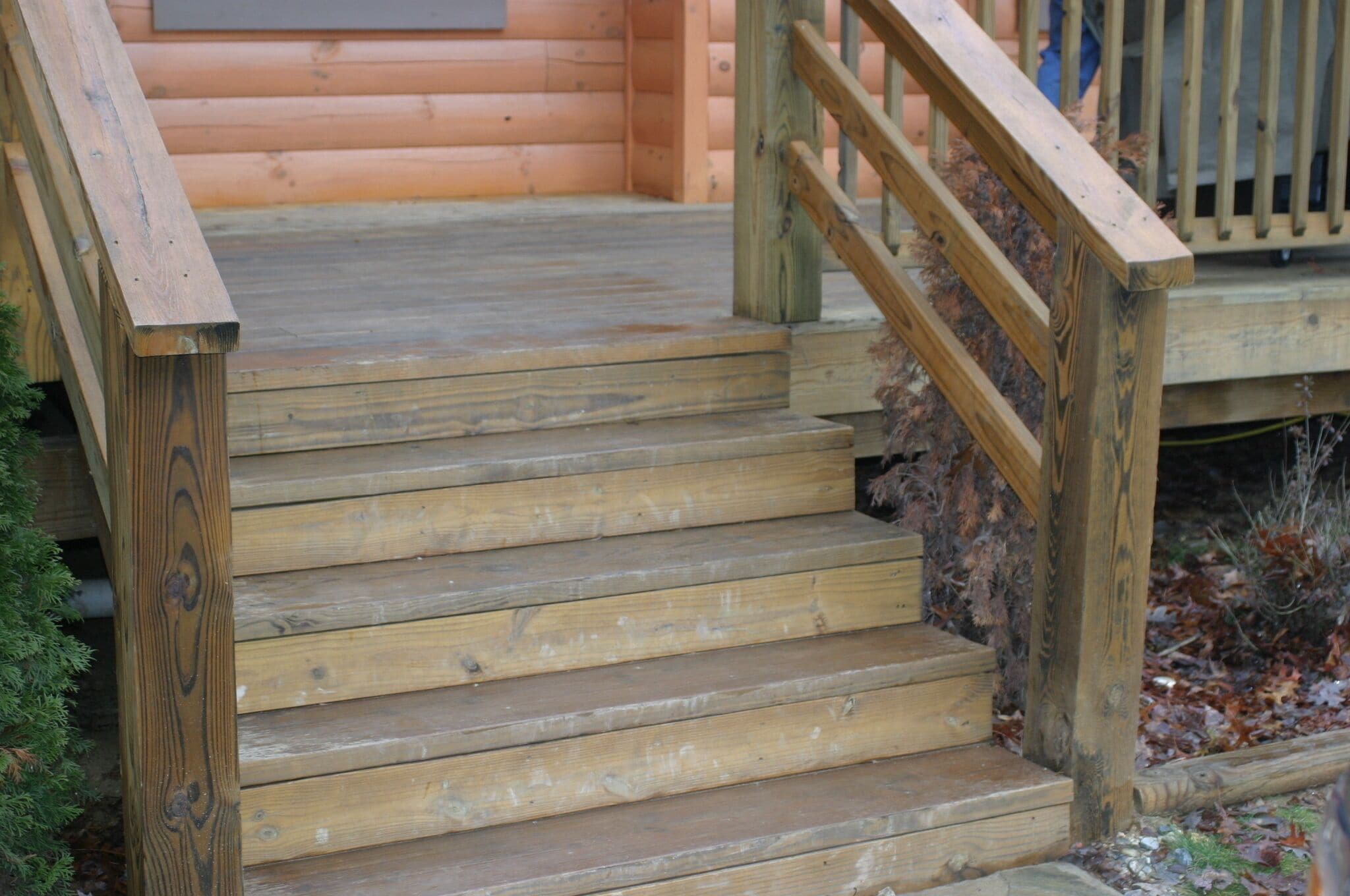 A wooden staircase leading up to a wooden deck with a railing.