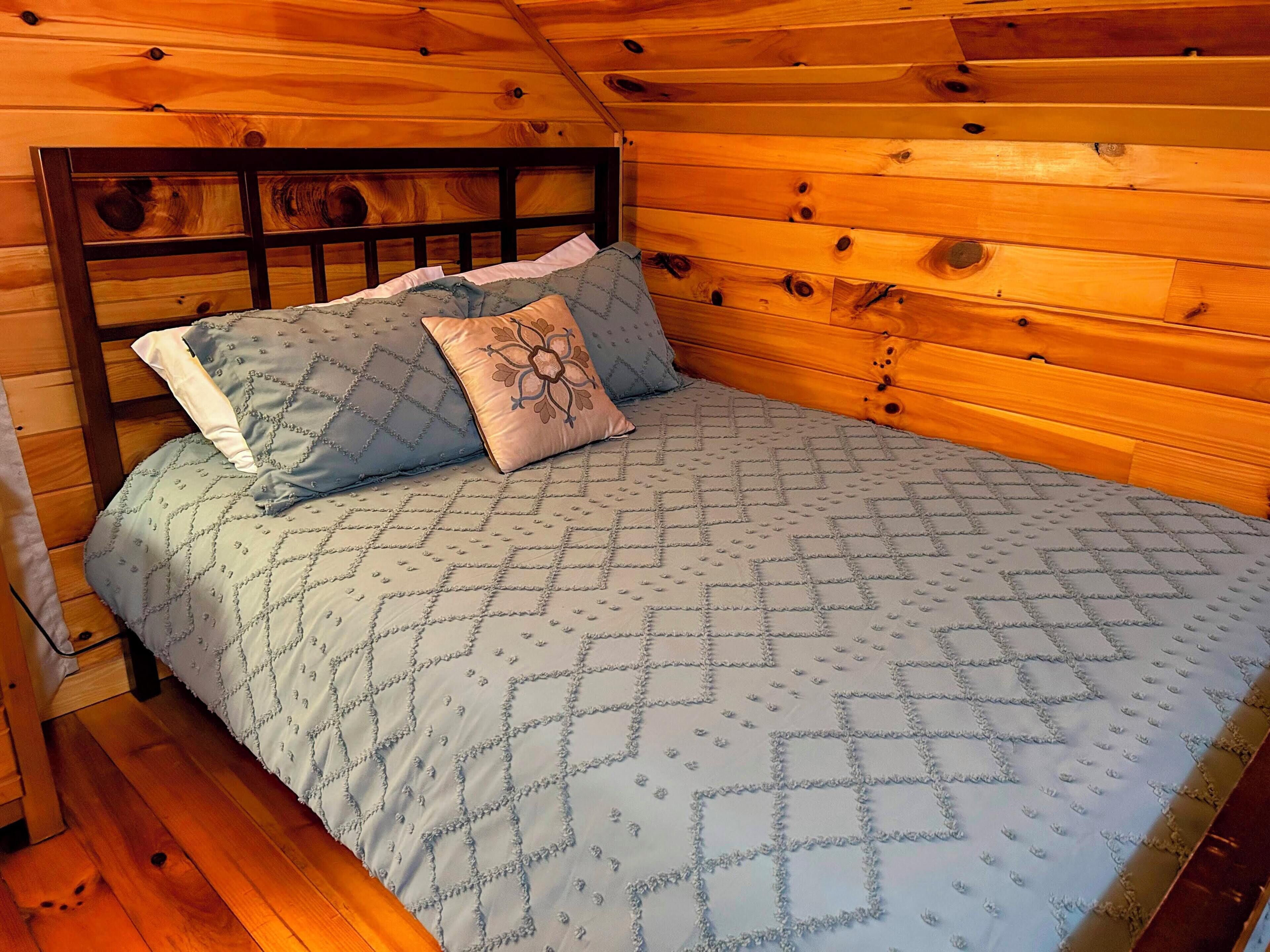 Une chambre dans une cabane en bois, avec un lit, des oreillers et une tête de lit.