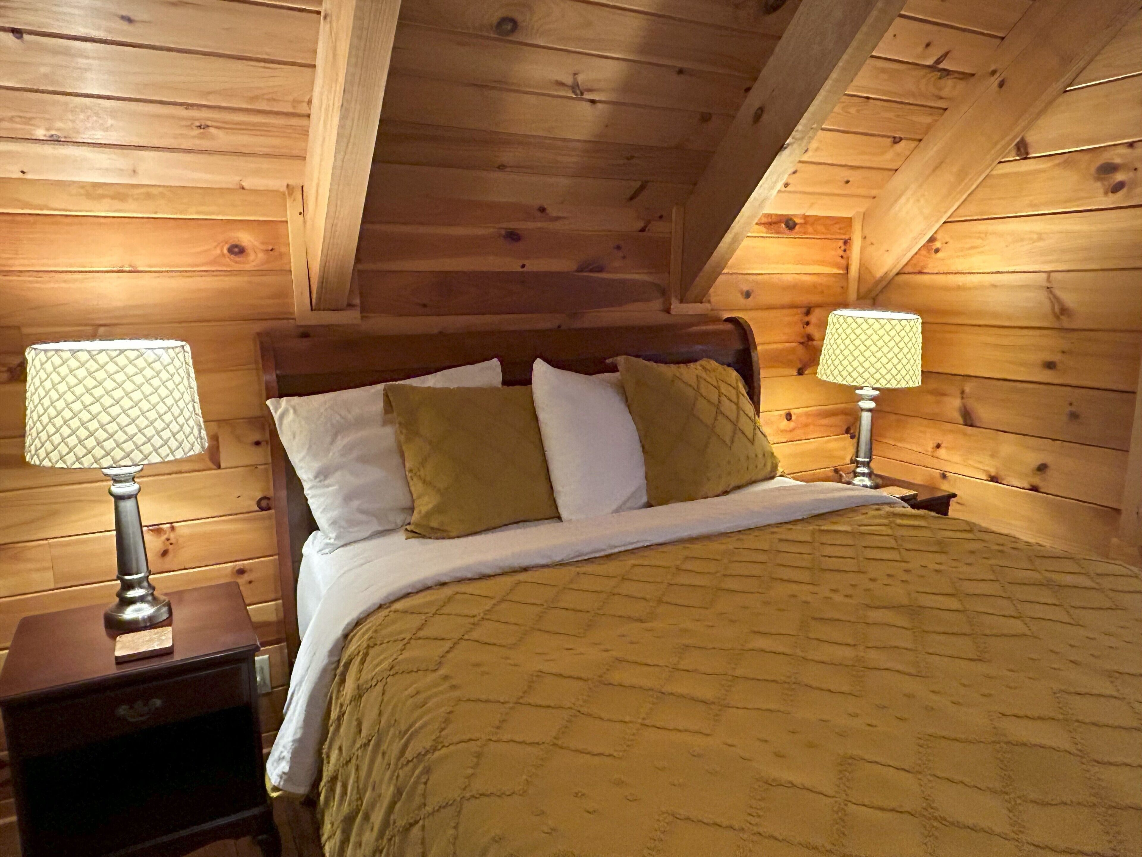 Une chambre dans une cabane en bois, avec un lit, deux lampes de chevet et une table de chevet.