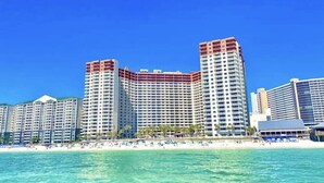 A beachfront hotel with multiple high-rise buildings, a sandy beach, and clear blue water.