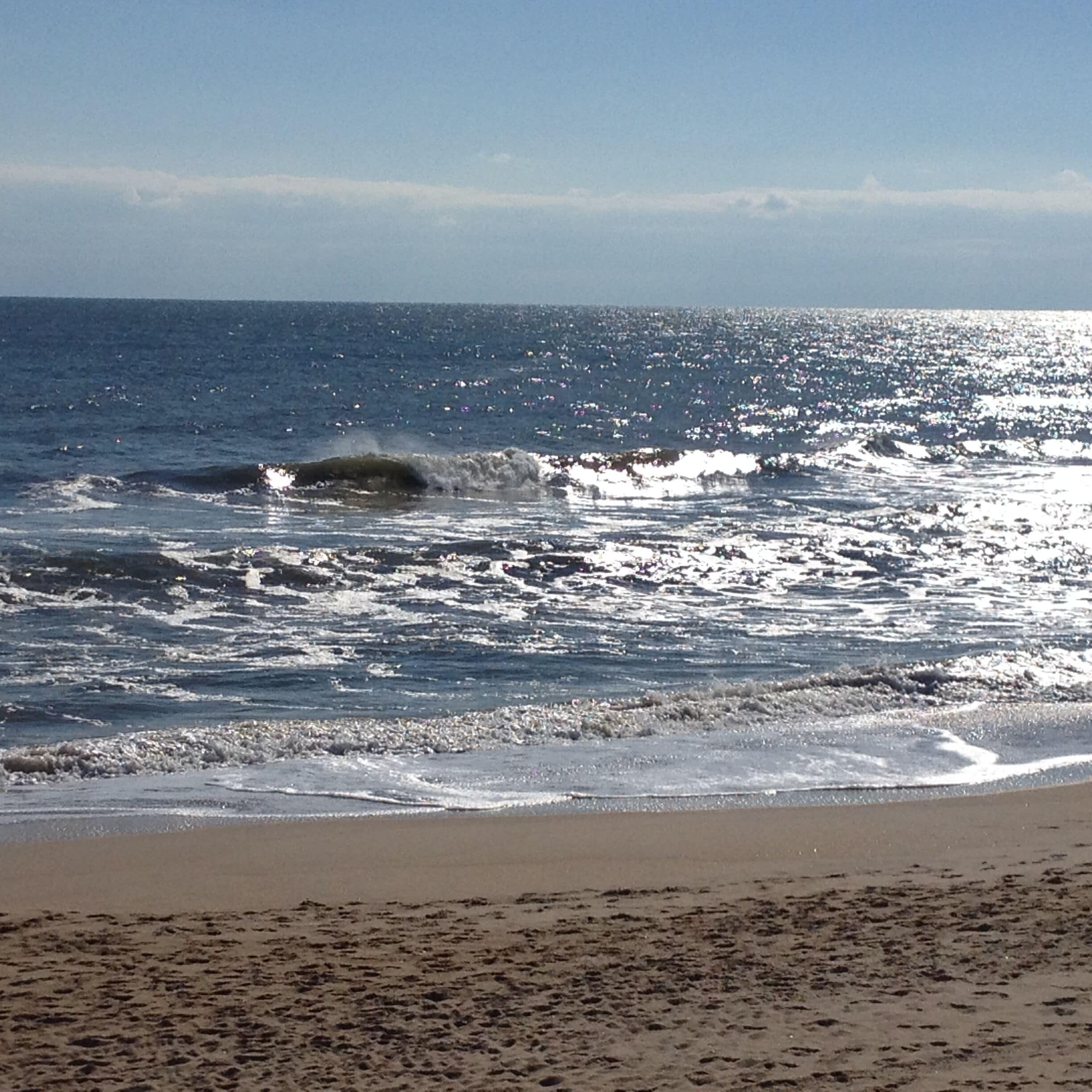Een strand met golven en een heldere lucht.