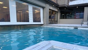 Una piscina con bordo piastrellato, ampie finestre e un edificio con facciata in mattoni.