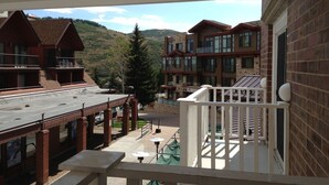 Un balcone con vista su una montagna, un edificio con facciata in mattoni e un pontile in legno.