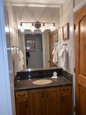 A bathroom with a granite countertop, a sink, wooden cabinets, and a mirror with three lights above it. - Awesome Ski In Ski Out, K, 2Q, at Resort Plaza, Pool, Hot Tub, Sleeps 8 #68619 (Park City)
