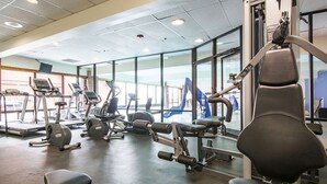 Una palestra con diverse attrezzature per l'esercizio fisico, tra cui tapis roulant, cyclette e macchinari per pesi.
