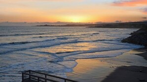 A beach at sunset with waves, a wooden boardwalk, and a distant shoreline. - Villa Vista Lower (Santa Cruz)
