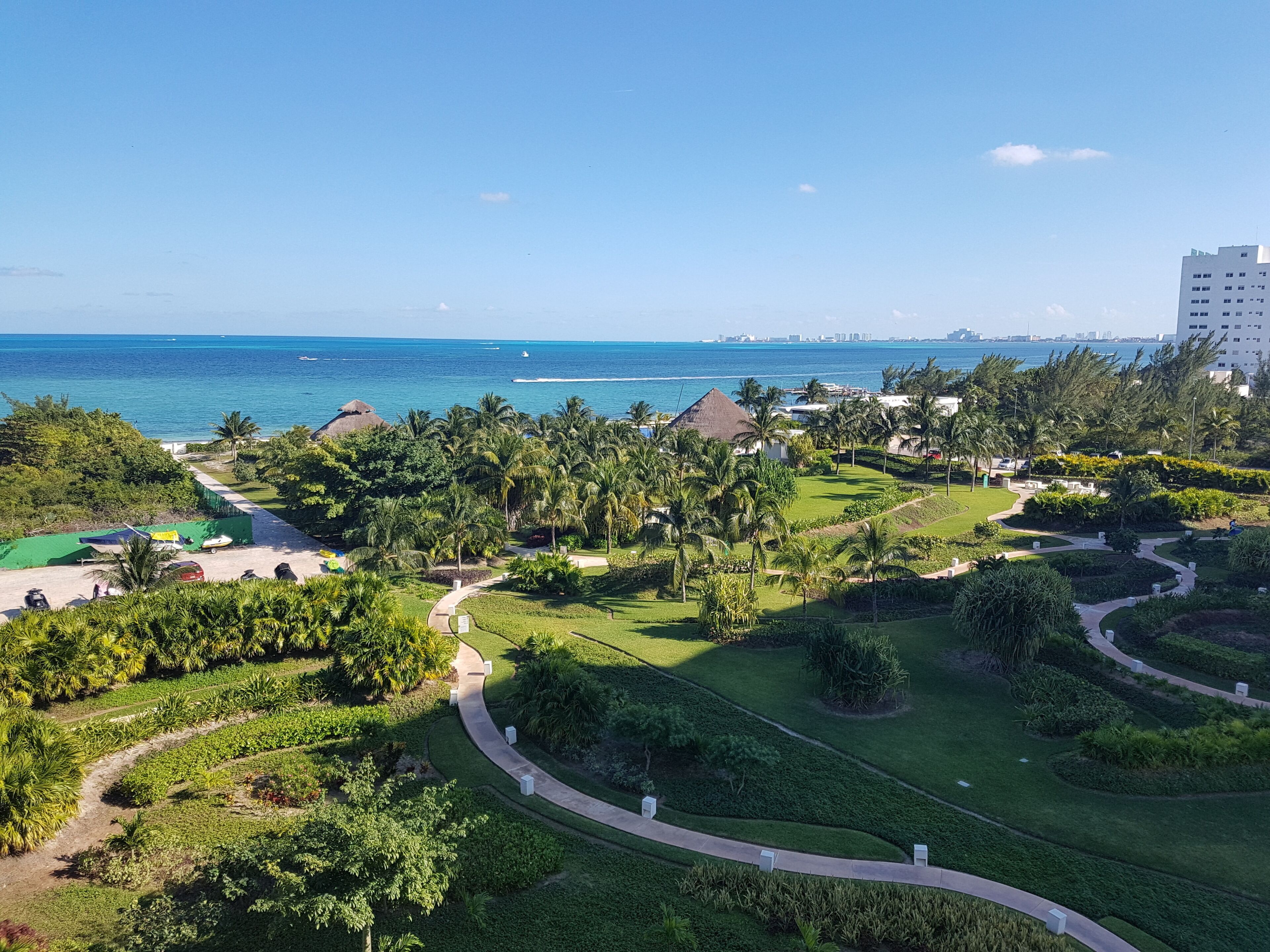 A resort with a golf course, palm trees, and a view of the ocean.