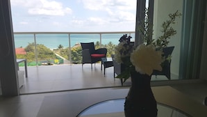 A balcony with a view of the ocean, a chair, a table, and a vase with flowers. - Oceanside, spectacular views, very big 2 bdr condo in Cancun (Cancún)