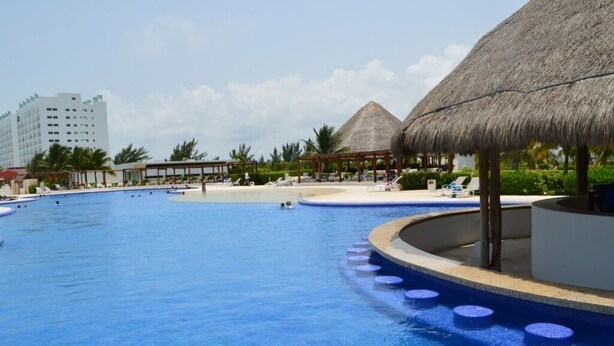 A large swimming pool with a thatched-roof structure and lounge chairs. - Oceanside, spectacular views, very big 2 bdr condo in Cancun (Cancún)