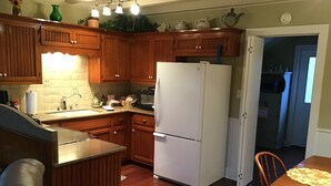 A kitchen with wooden cabinets, a white refrigerator, a sink, and a dining table with chairs. - ACE OF HEARTS The perfect getaway! Only 3.5 miles from Main Street. (Fredericksburg)