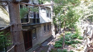 Ein rustikales Haus mit Backsteinfassade, einer Holzdielen-Terrasse und einem Kiesweg zum Eingang.