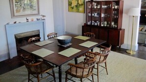 Ein Esszimmer mit Holztisch, sechs Stühlen, einem Kamin, einer Speisekammer und zwei gerahmten Kunstwerken an der Wand.