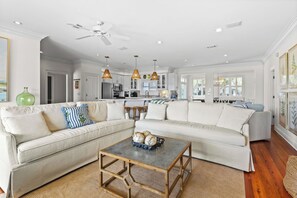 A spacious living room with a large sectional sofa, a coffee table, and a ceiling fan.