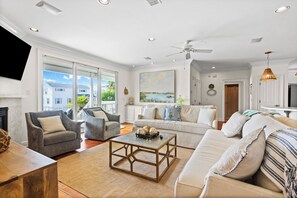 A spacious living room with a large window, a ceiling fan, and a fireplace.