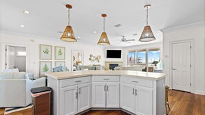 A spacious kitchen with white cabinetry, a large island, and three hanging wicker pendant lights. - 🌞 The Sunshine Gulfside | Sleeps 22 w/ Private Pool + Steps to Beach (Pensacola Beach)