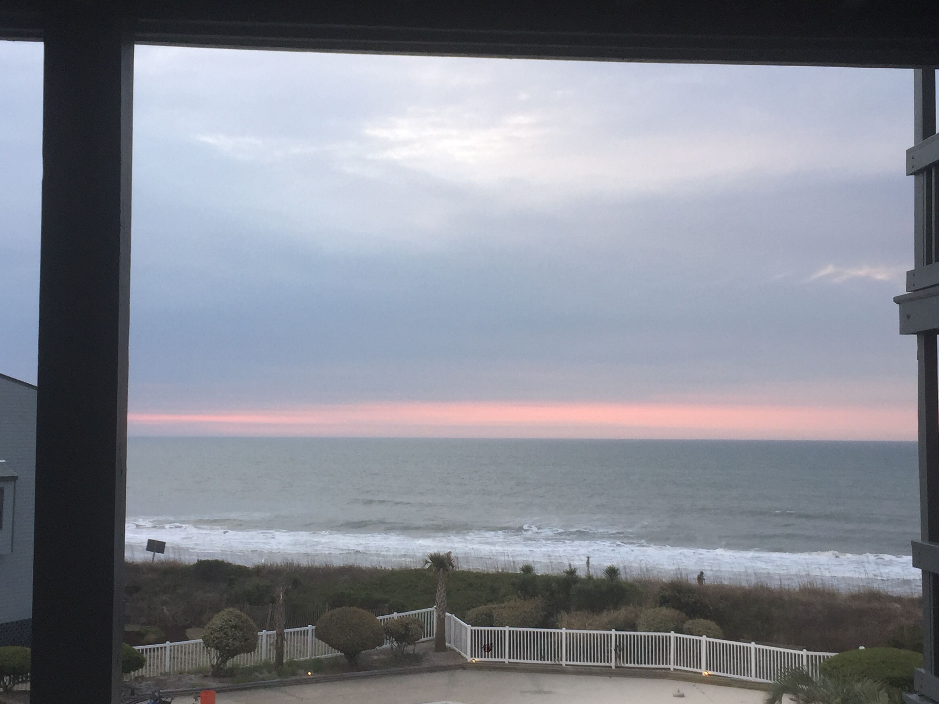 Un balcón con vista al océano y al atardecer.