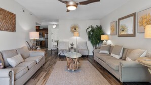 Un salon moderne avec deux canapés, une table basse et un ventilateur de plafond.
