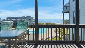 Un balcon avec vue sur une piscine et l’océan.