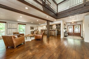 A spacious living area with hardwood floors, leather furniture, and a high ceiling with exposed beams. - Beautiful Lakefront Lodge.  Tannenbaum Lodge - family or business destination.  (Drasco)