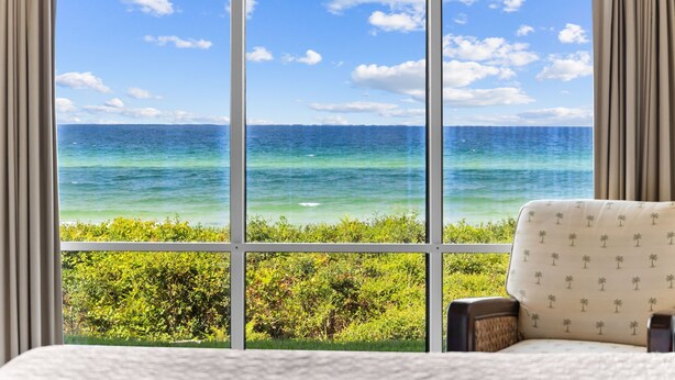 Una habitación con un ventanal grande que ofrece vistas al océano y la vegetación.