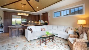 A spacious living room with a large sectional sofa, a glass coffee table, and a ceiling fan.