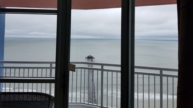 A balcony with a view of the ocean and a distant pier. - Oceanfront Penthouse Suite - Prince Resort (Myrtle Beach)