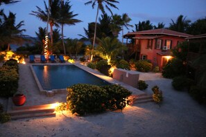 A swimming pool surrounded by palm trees and a red building.