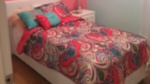 Une chambre à coucher avec un lit, une table de chevet et une lampe.