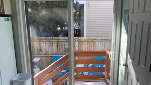 A room with a sliding glass door leading to a wooden deck, a trash bin, and a colorful mat at the door. - Family Friendly Townhome W/POOL In Ocean City, Md. (Ocean City)